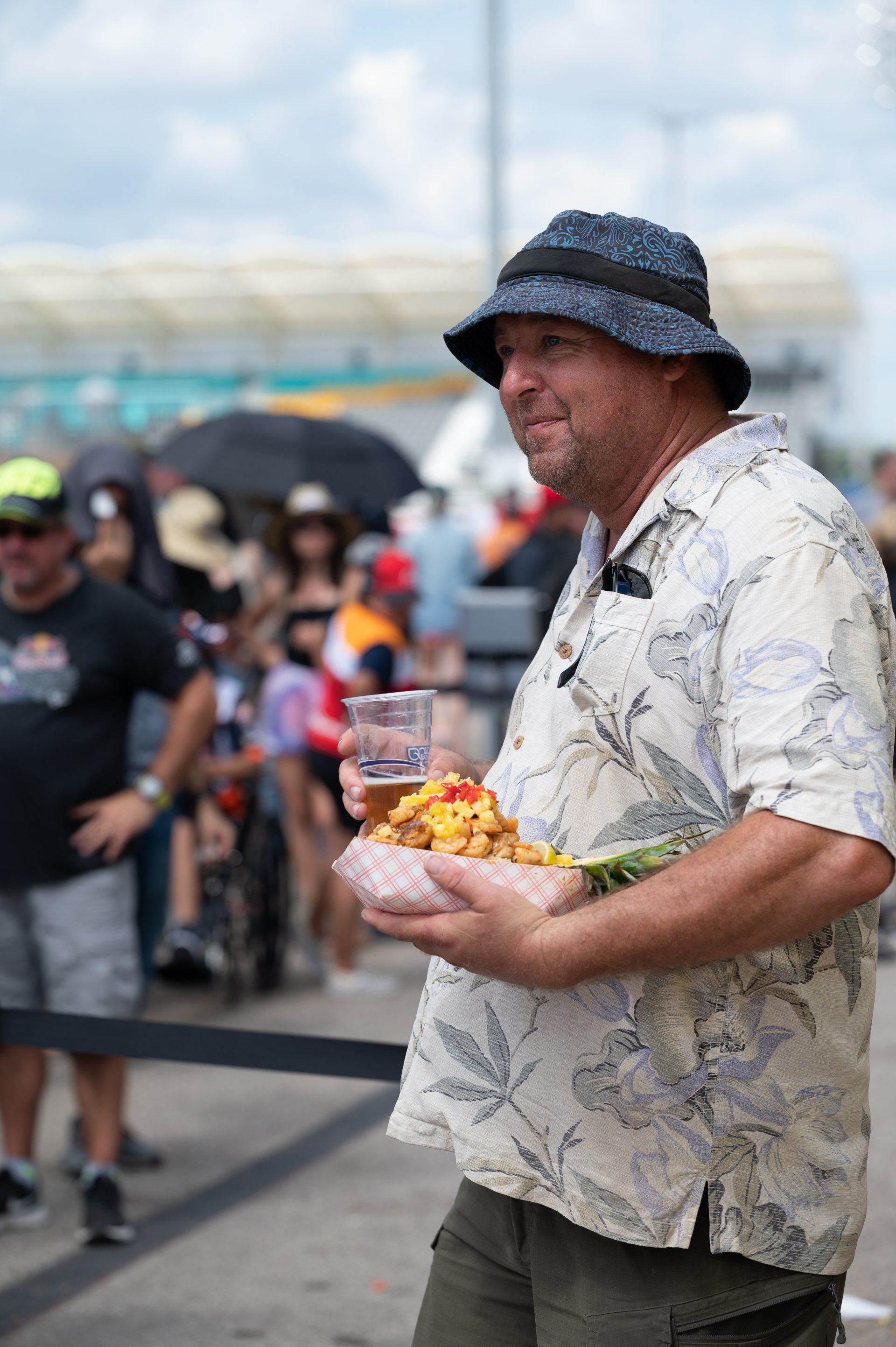 A race fan in a Hawaiian shirt with a pineapple bowl in the grandstands