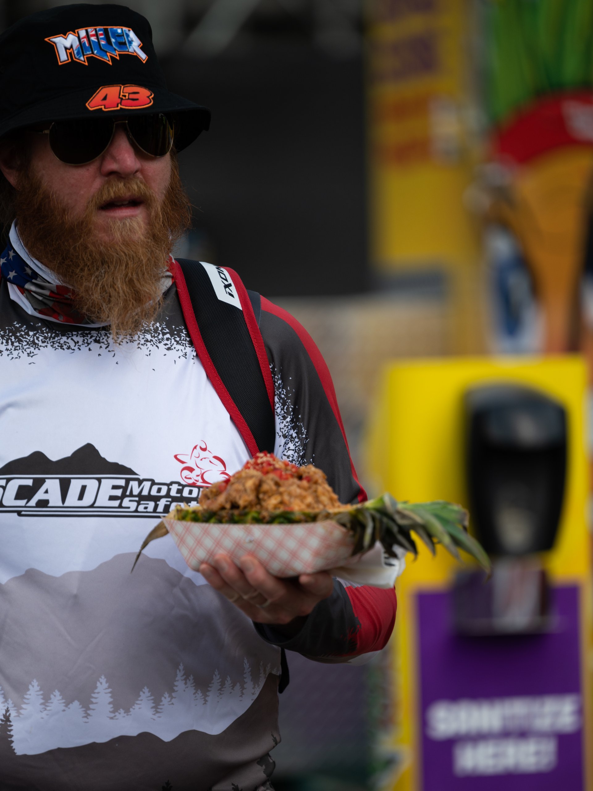 A MotoGP fan holding the loaded carved-pineapple bowl at the event